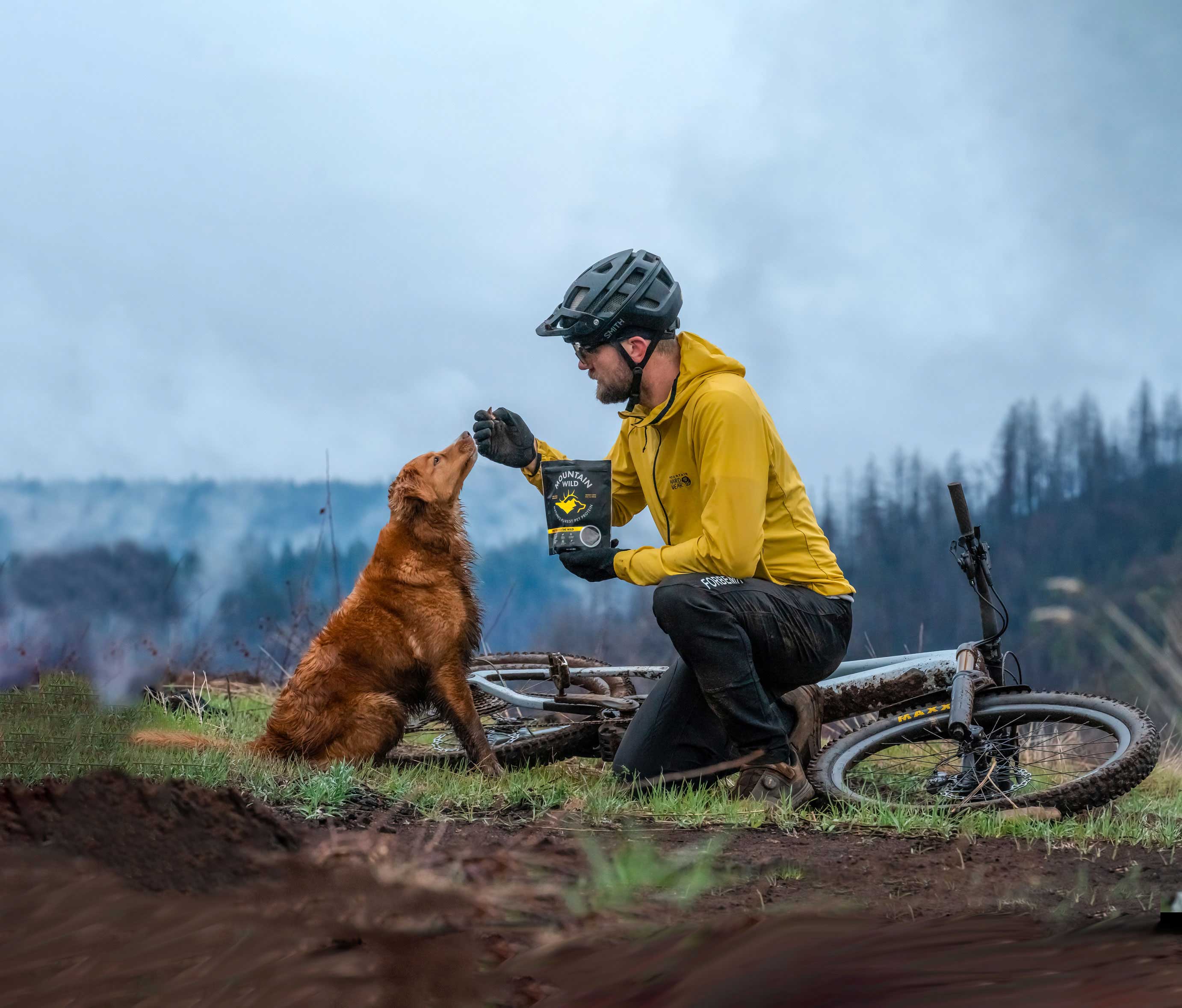 A mountain biker feeding his dog Mountain Wild dog treats after a mountain bike ride in the mountains.