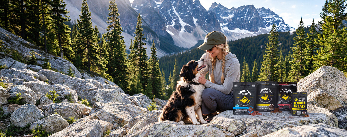 Woman and her dog on a mountain ridge at sunset with Mountain Wild treat bags